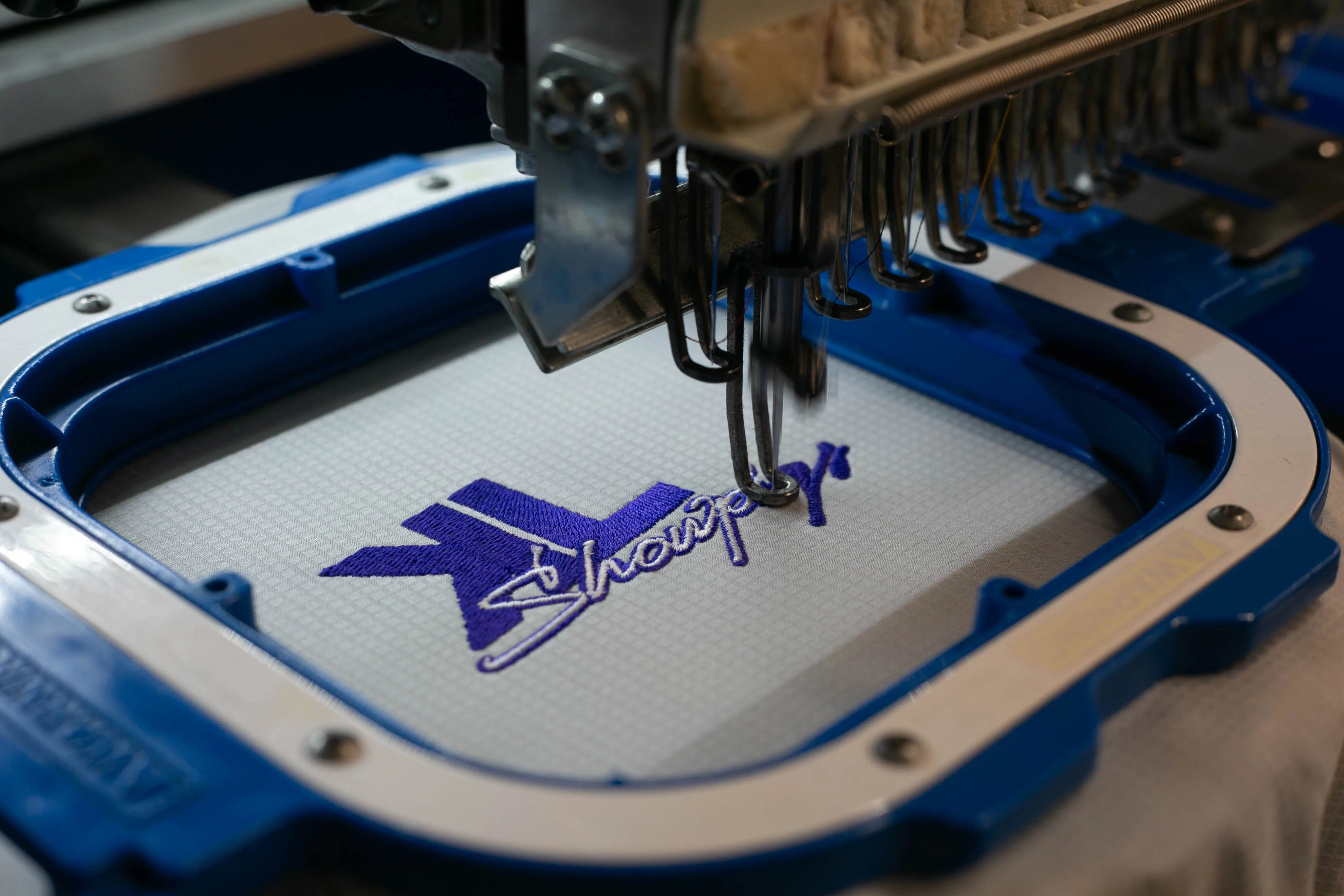 Left-chest logo embroidery in progress on a polo